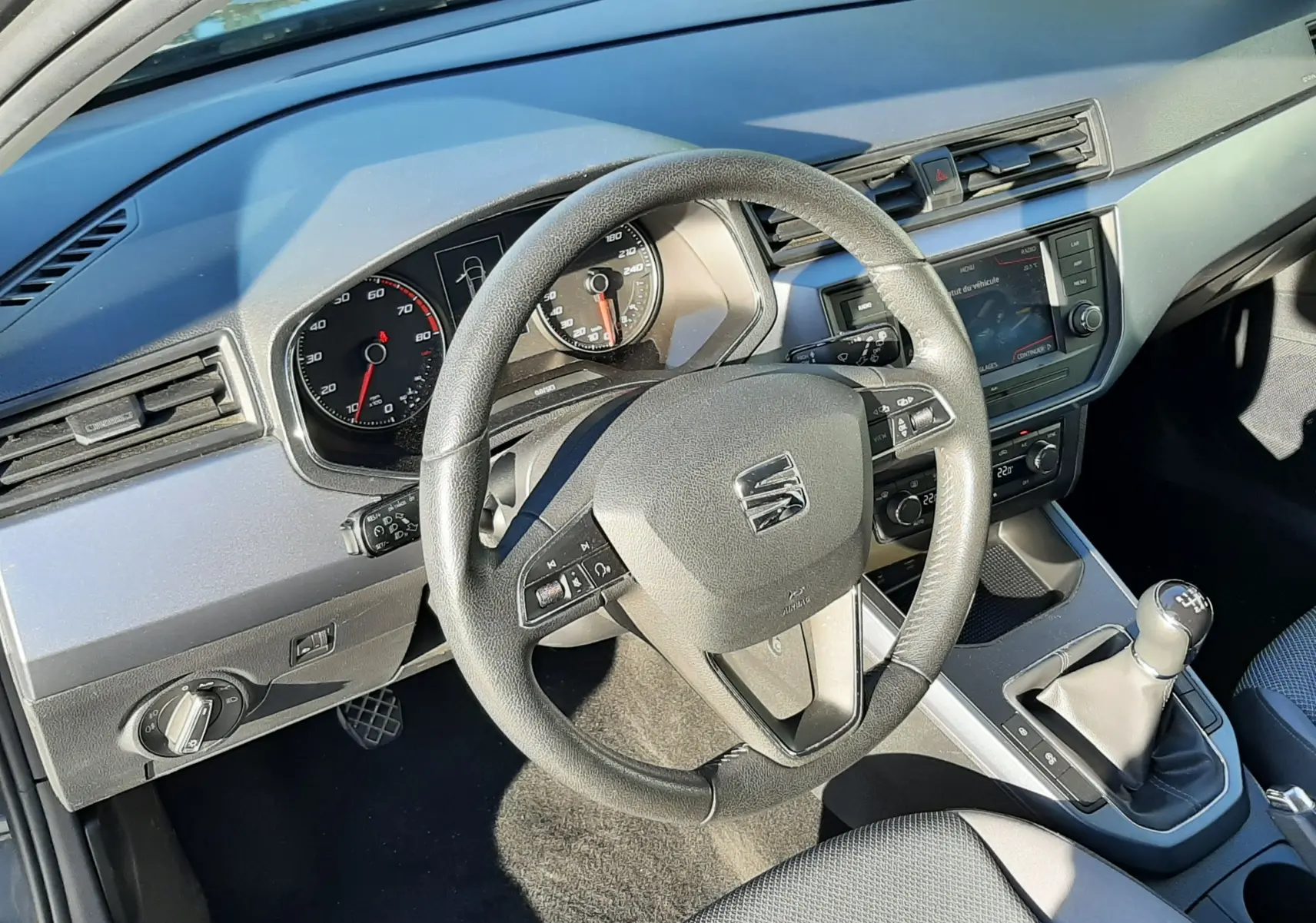 Vue intérieure du poste de conduite du SEAT Arona 2019, volant multifonction et levier de vitesse manuel visibles.