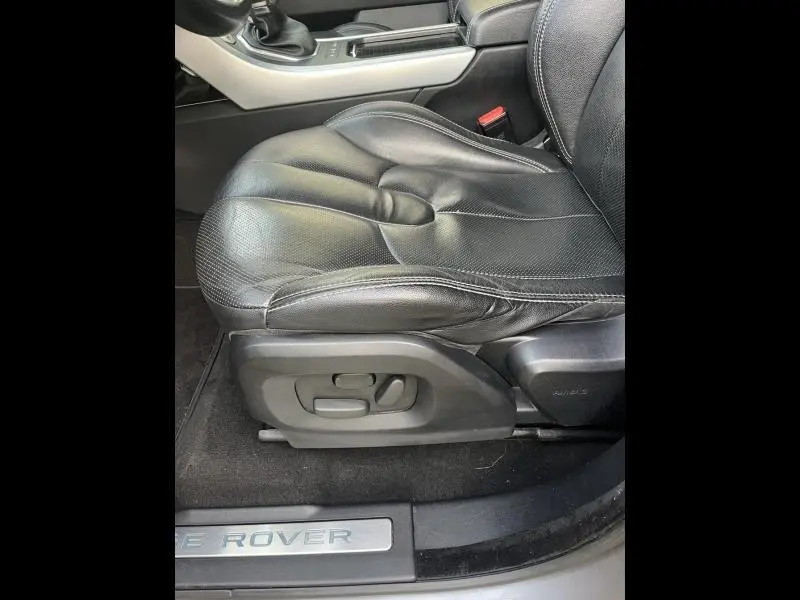 Gros plan sur le siège conducteur en cuir noir du Range Rover Evoque 2.2 Td4 Dynamic, avec commandes électriques et seuil de porte marqué Land Rover.