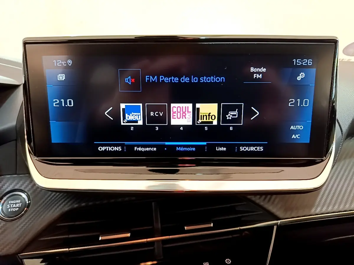 Écran tactile central de 7 pouces du tableau de bord de la Peugeot 208 gris clair, avec commandes climatisation et bouton start/stop visible.