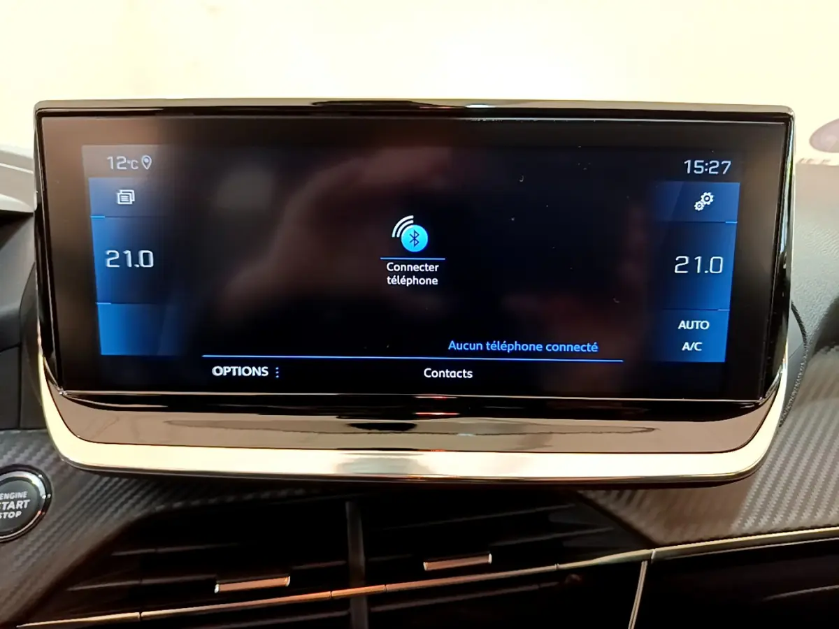 Écran tactile central de la Peugeot 208 gris clair affichant la connexion Bluetooth et la température à 21°C.