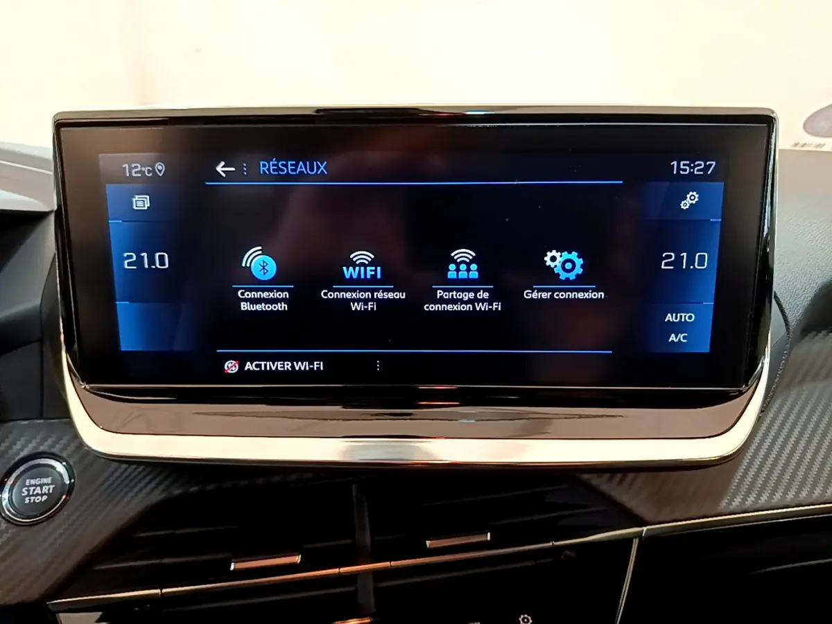 Écran tactile central de la Peugeot 208 PureTech 100, affichant les options de connexion réseau et climatisation à 21°C.