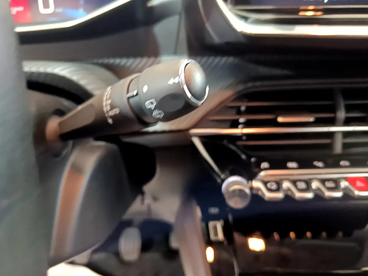 Gros plan sur la commande d’essuie-glace à gauche du volant dans l’habitacle gris clair de la Peugeot 208 2020.