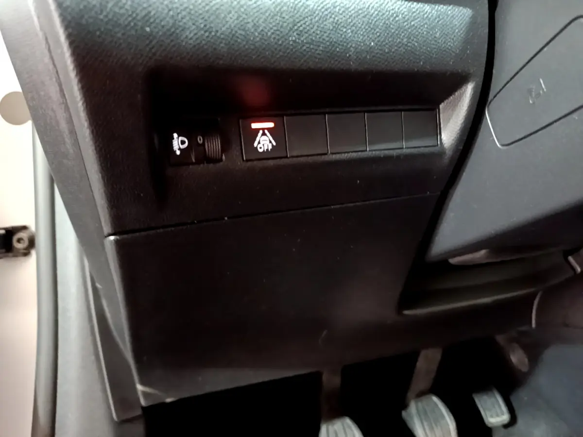 Détail du tableau de bord côté gauche d'une Peugeot 208 gris clair, avec bouton d'assistance à la conduite activé.
