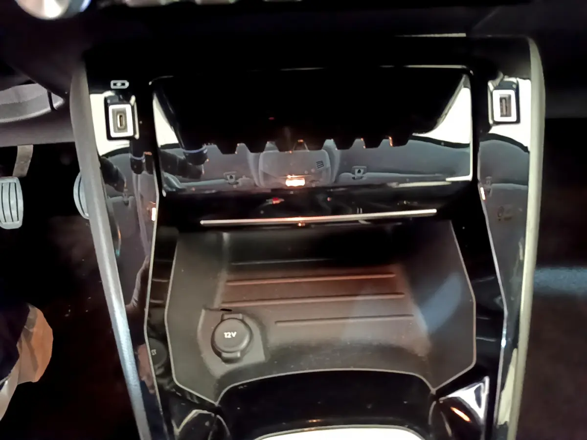 Vue rapprochée de la console centrale noire du Peugeot 208 2020 avec prise 12V et rangement sous tablette.