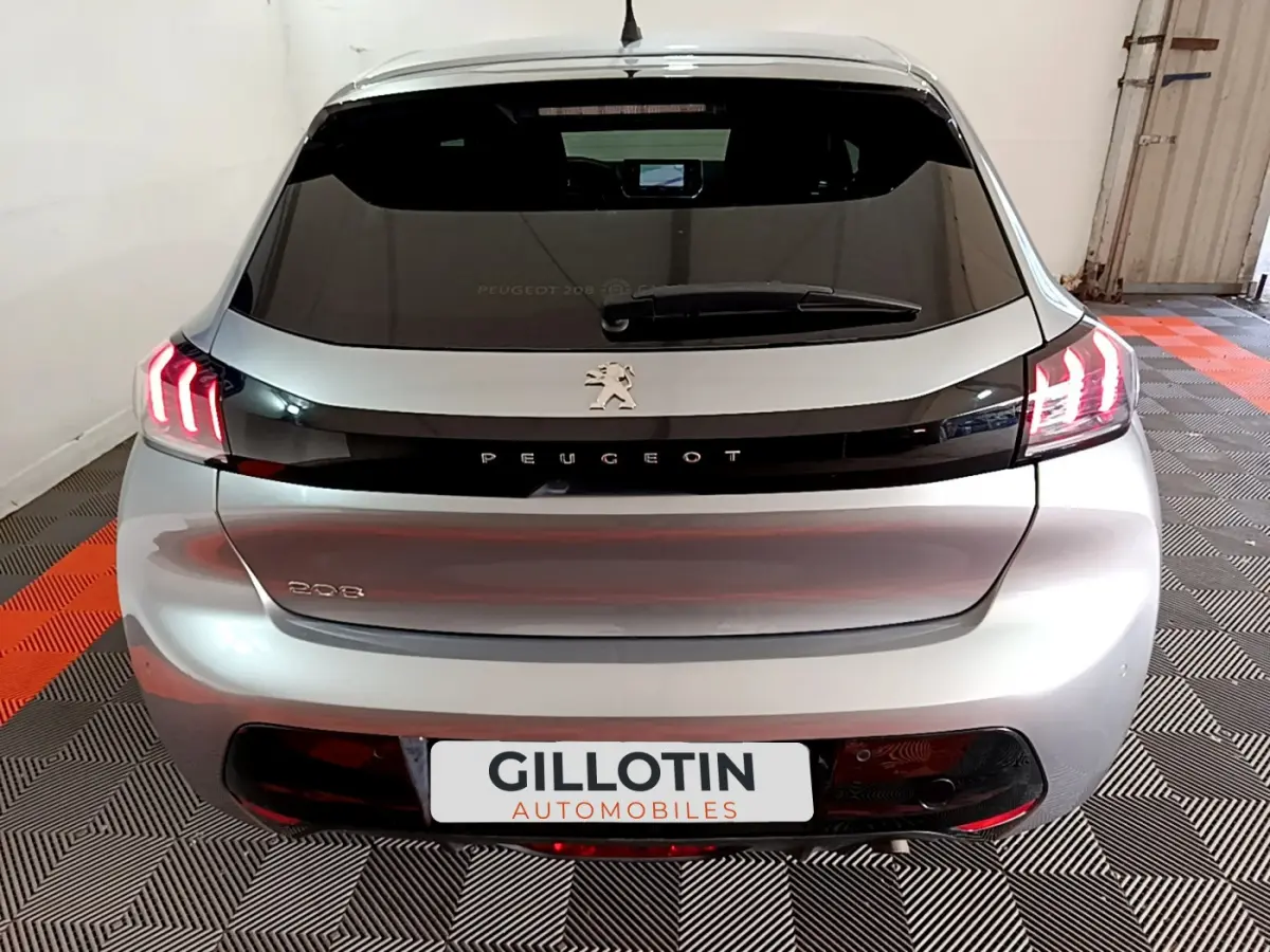Vue arrière d'une Peugeot 208 gris clair avec feux LED allumés dans un garage.