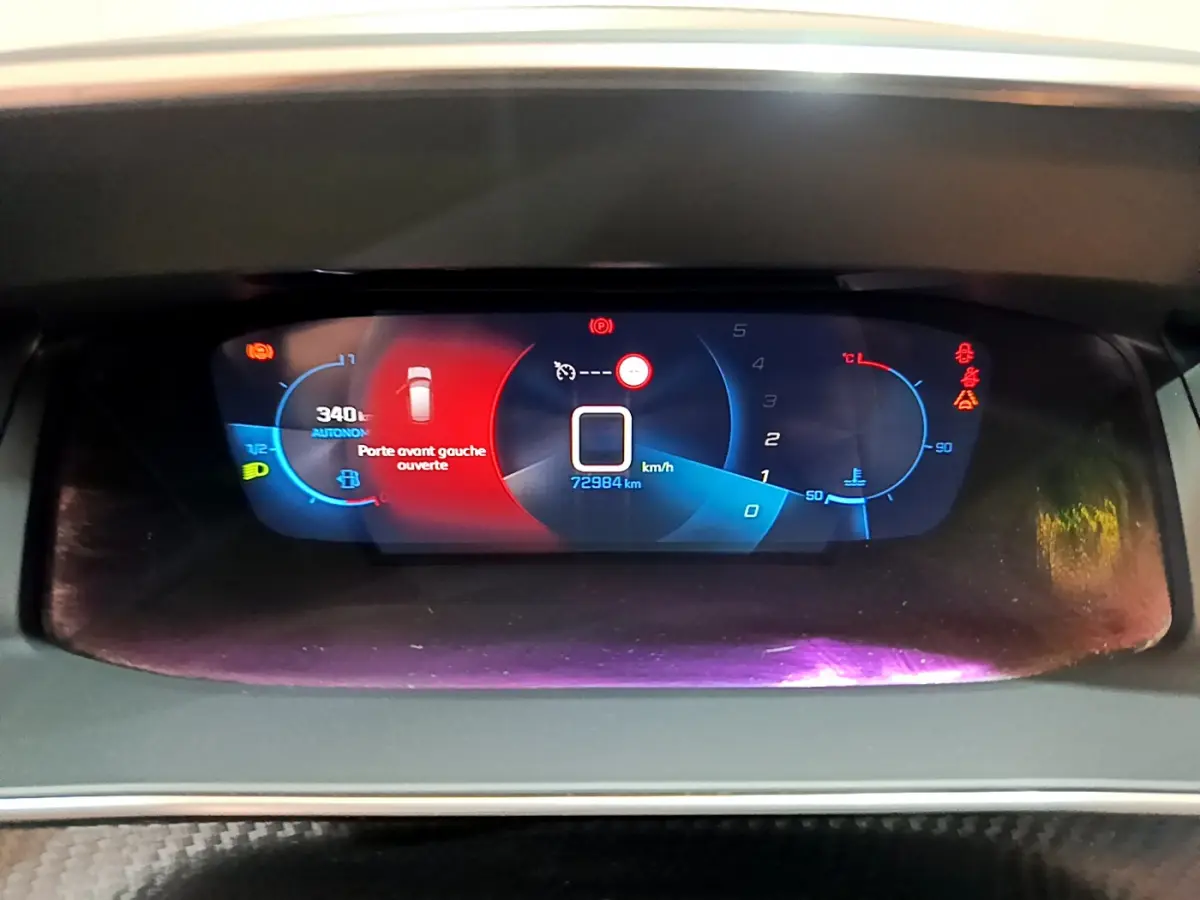Affichage numérique du tableau de bord de la Peugeot 208 PureTech 100, indiquant porte avant gauche ouverte et vitesse à zéro.