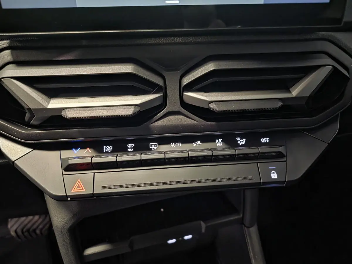 Vue rapprochée de la console centrale du Dacia Duster 2025, montrant les aérateurs gris acier et les commandes climatisation.