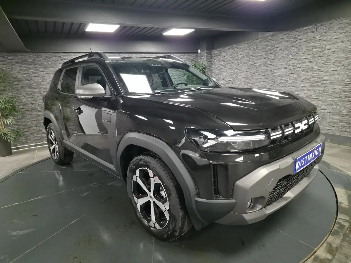 Vue 3/4 avant droit du Dacia Duster 1.6 Hybrid noir nacré avec jantes alliage et barres de toit noires.