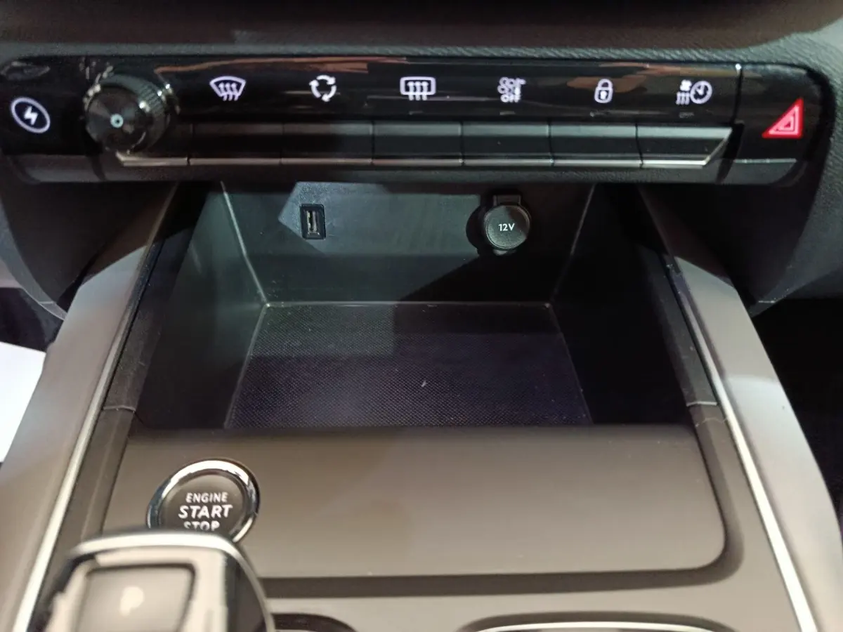 Vue rapprochée de la console centrale noire du Citroën C5 Aircross Hybrid avec bouton démarrage et prises USB et 12V visibles.