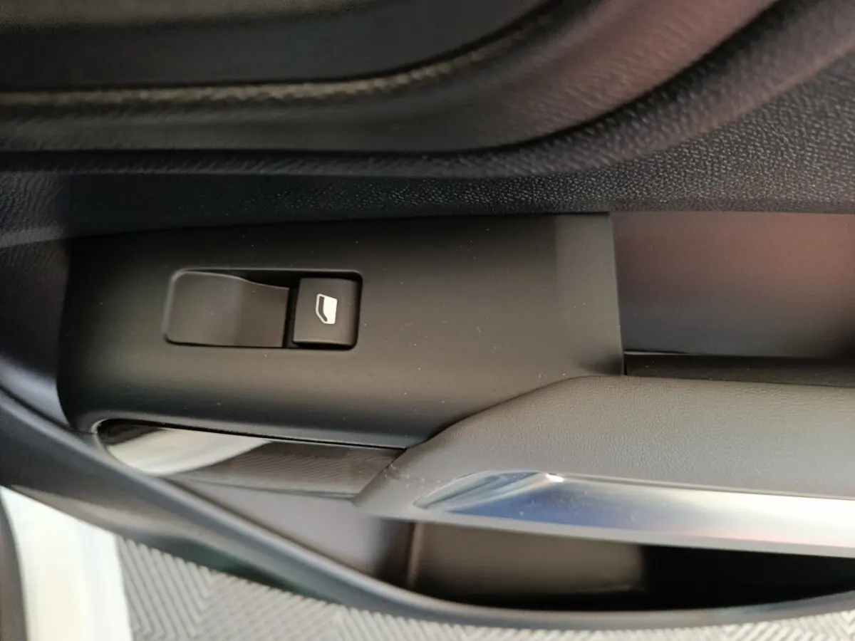 Bouton de commande de vitre sur la portière intérieure côté conducteur du Citroën C5 Aircross blanc, vue rapprochée.