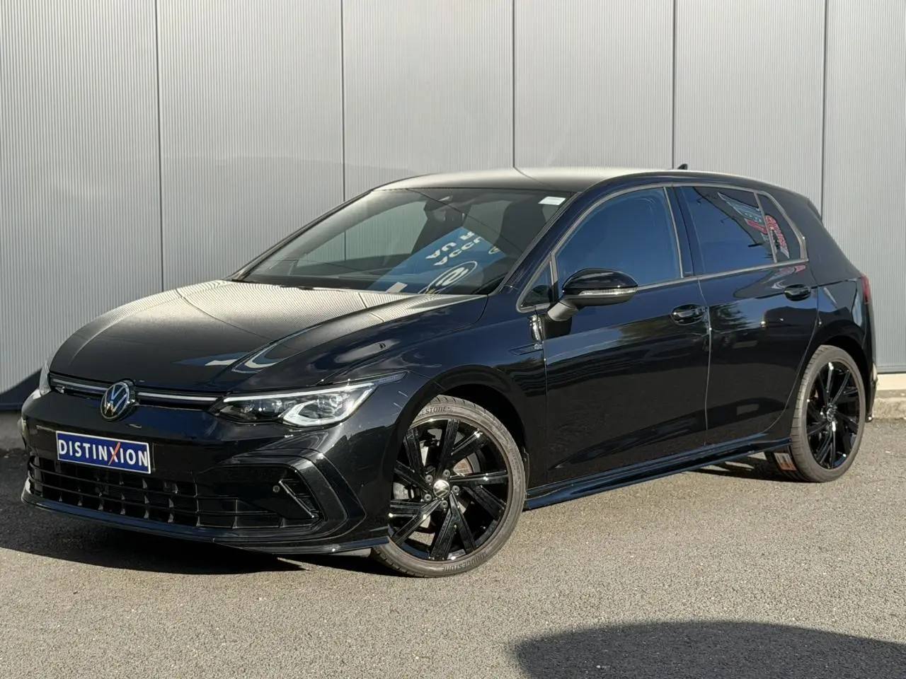 Volkswagen Golf 8 R-Line noire vue 3/4 avant droit avec jantes noires et vitres surteintées.