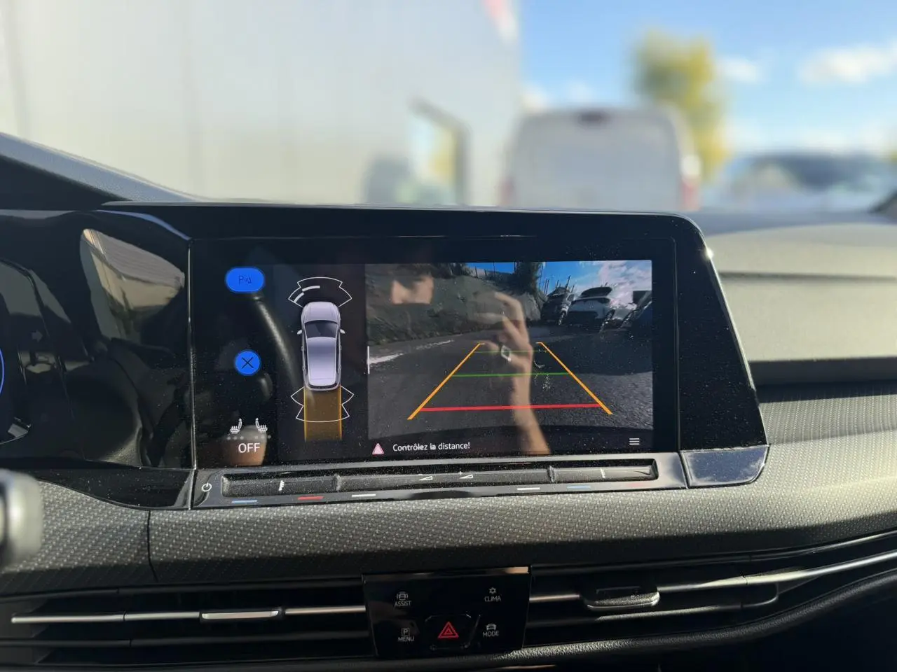 Vue intérieure centrée sur l'écran tactile affichant la caméra de recul de la Volkswagen Golf 8 noire de 2024.