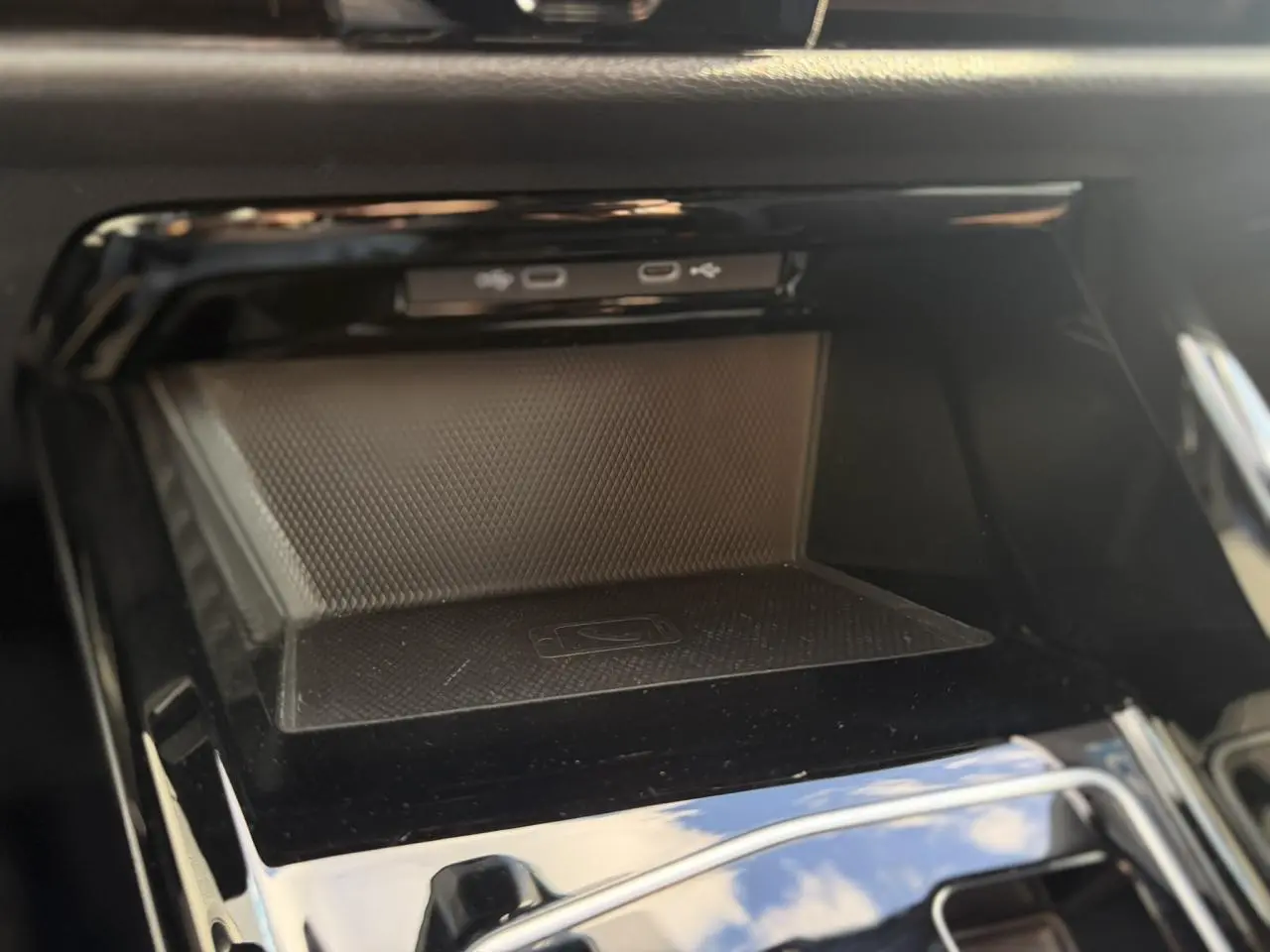 Gros plan sur la console centrale noire de la Volkswagen Golf 8 avec espace de rangement et ports USB visibles.