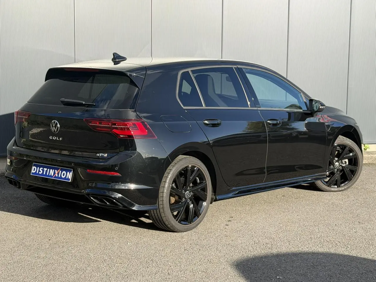 Volkswagen Golf 8 noir vue 3/4 arrière droit avec jantes noires et attelage escamotable visible.