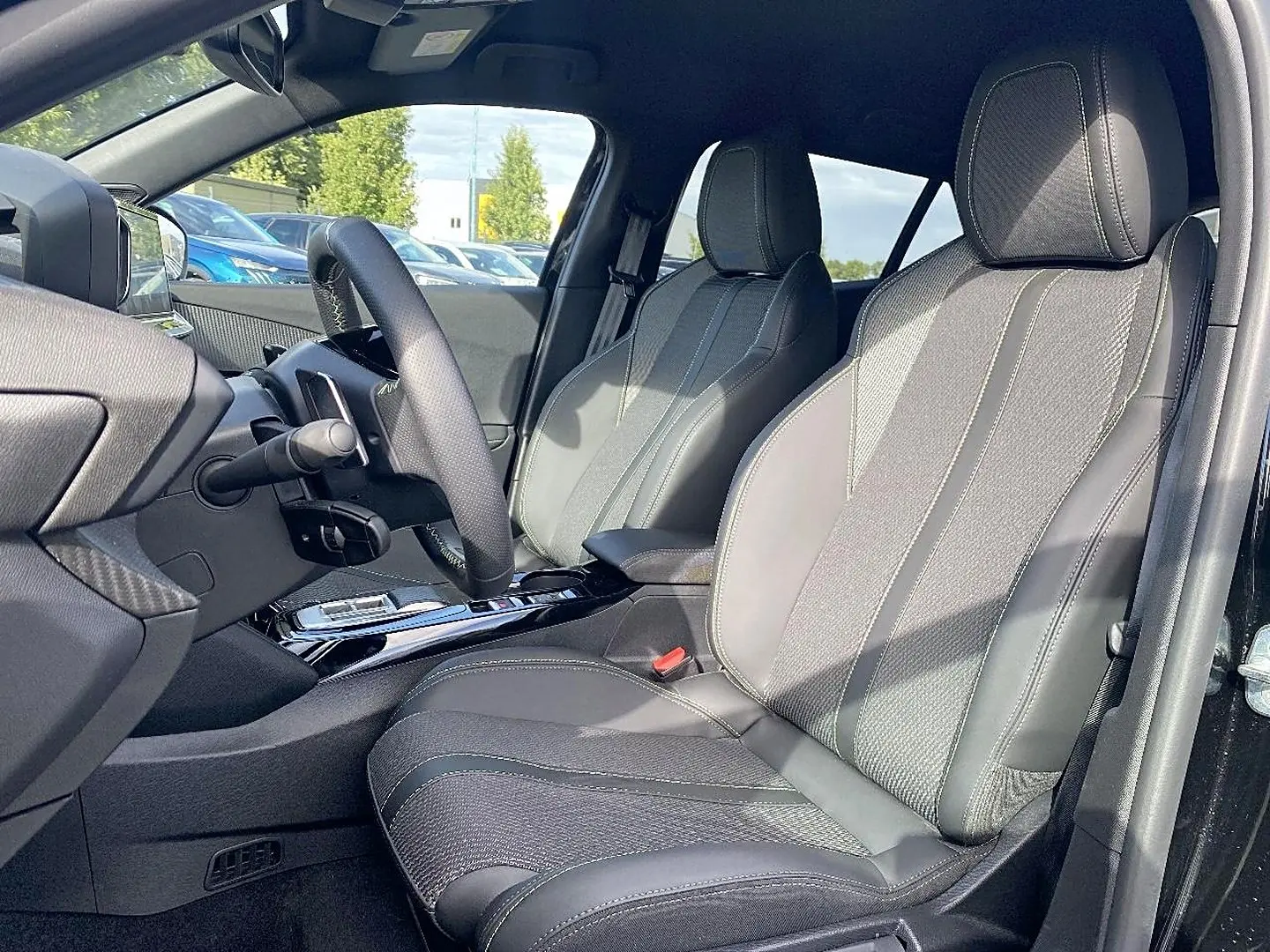 Vue intérieure côté conducteur du Peugeot 2008 noir 2025, montrant sièges en cuir et volant multifonction.