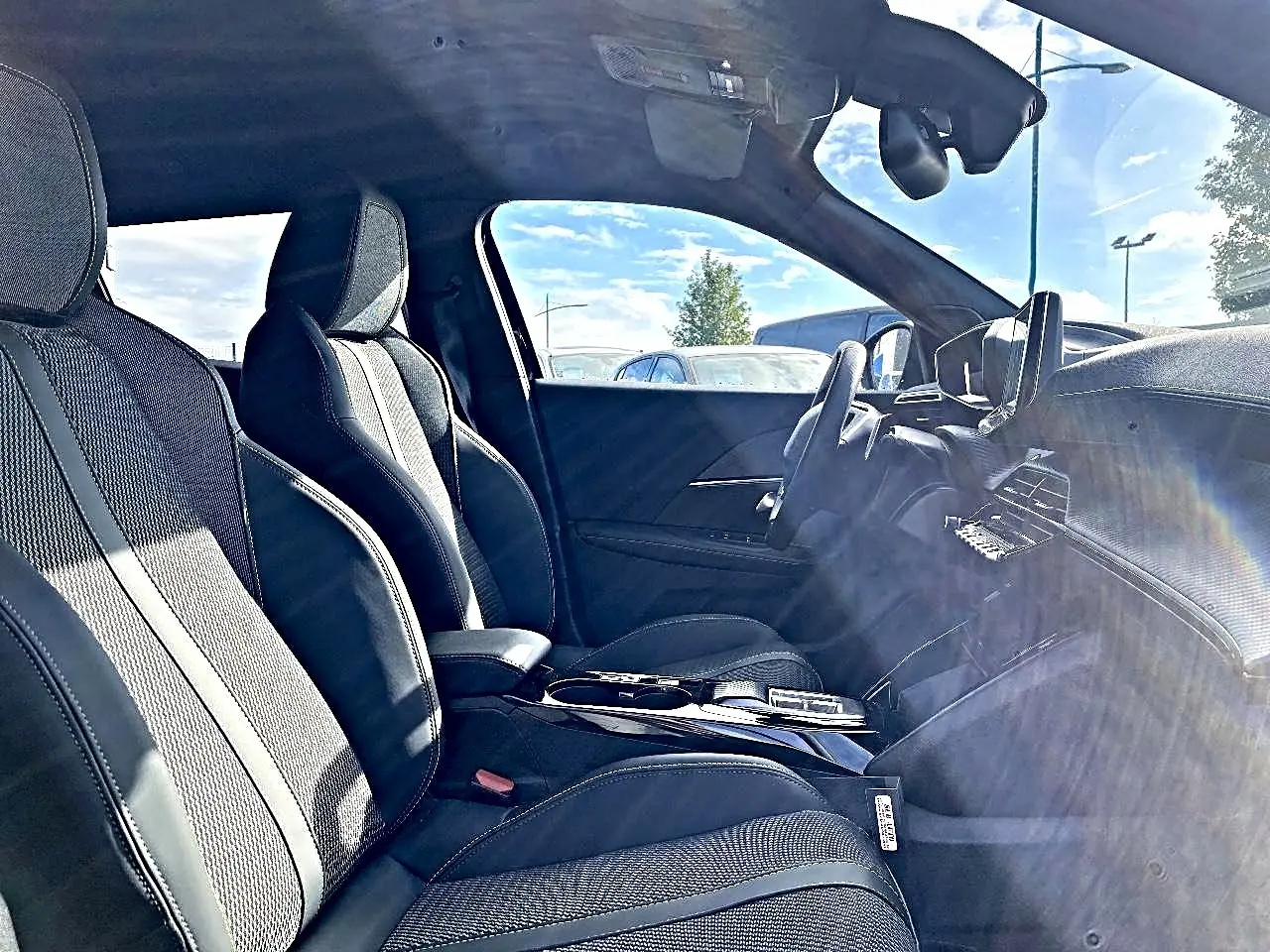 Vue intérieure côté conducteur du Peugeot 2008 noir 2025, mettant en valeur les sièges sport et le tableau de bord moderne.