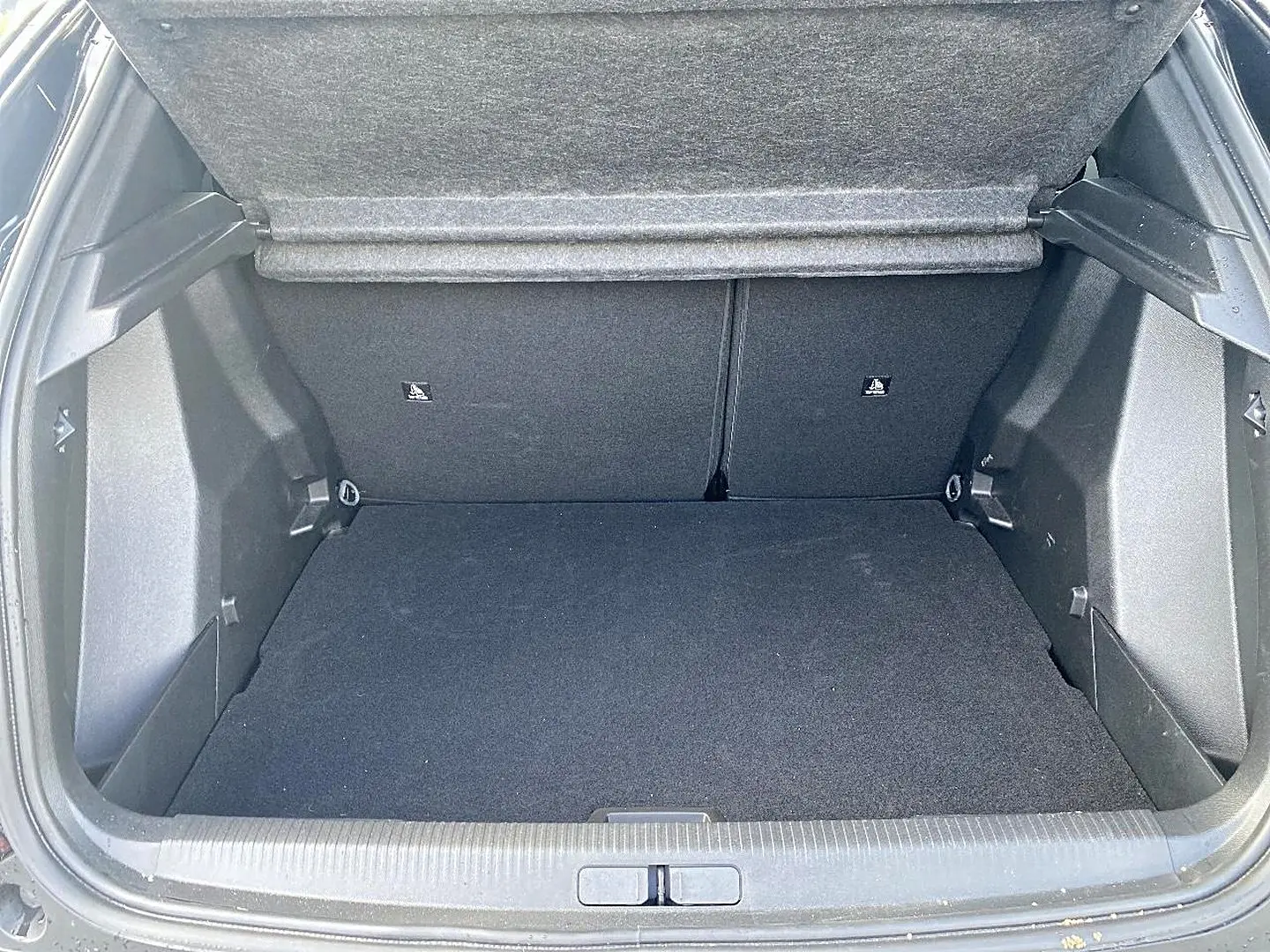 Coffre ouvert vu de l'arrière d'un Peugeot 2008 noir, montrant un espace de chargement propre et spacieux.
