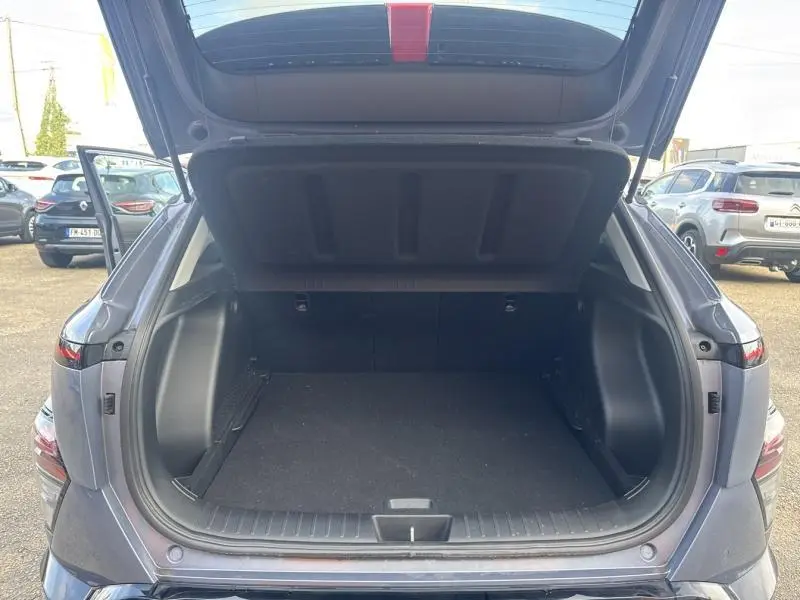 Coffre ouvert vu de l'arrière d'un Hyundai Kona Electric 2023 Metal Blue métallisé, espace de chargement vide.