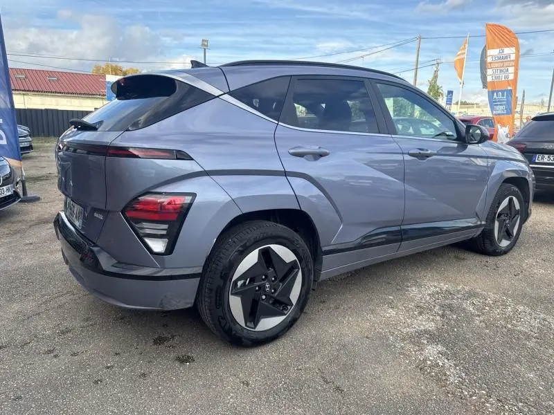 Vue 3/4 arrière droite du Hyundai KONA Electric 2023 en Metal Blue métallisé avec jantes alu distinctives.