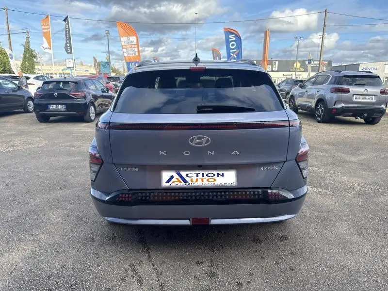 Vue arrière d'une Hyundai KONA Electric 2023 Metal Blue métallisé avec feux arrière LED continus et lunette arrière surteintée.