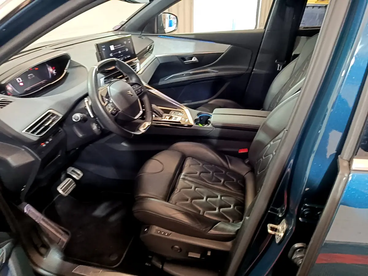 Vue intérieure côté conducteur du Peugeot 5008 bleu 2021, avec sièges cuir noirs et tableau de bord digital moderne.