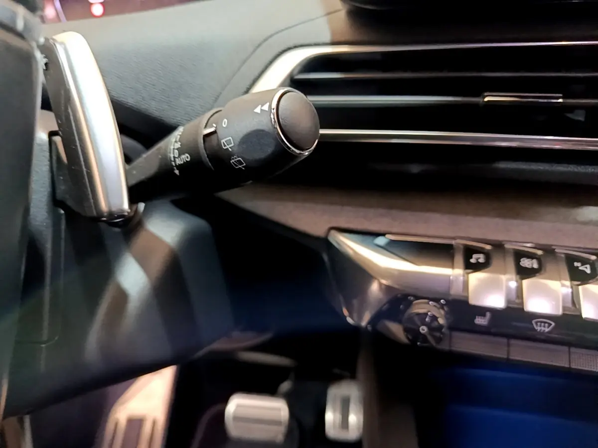 Détail intérieur du Peugeot 5008 bleu 2021 montrant la commande d'essuie-glace et les boutons de climatisation côté conducteur.