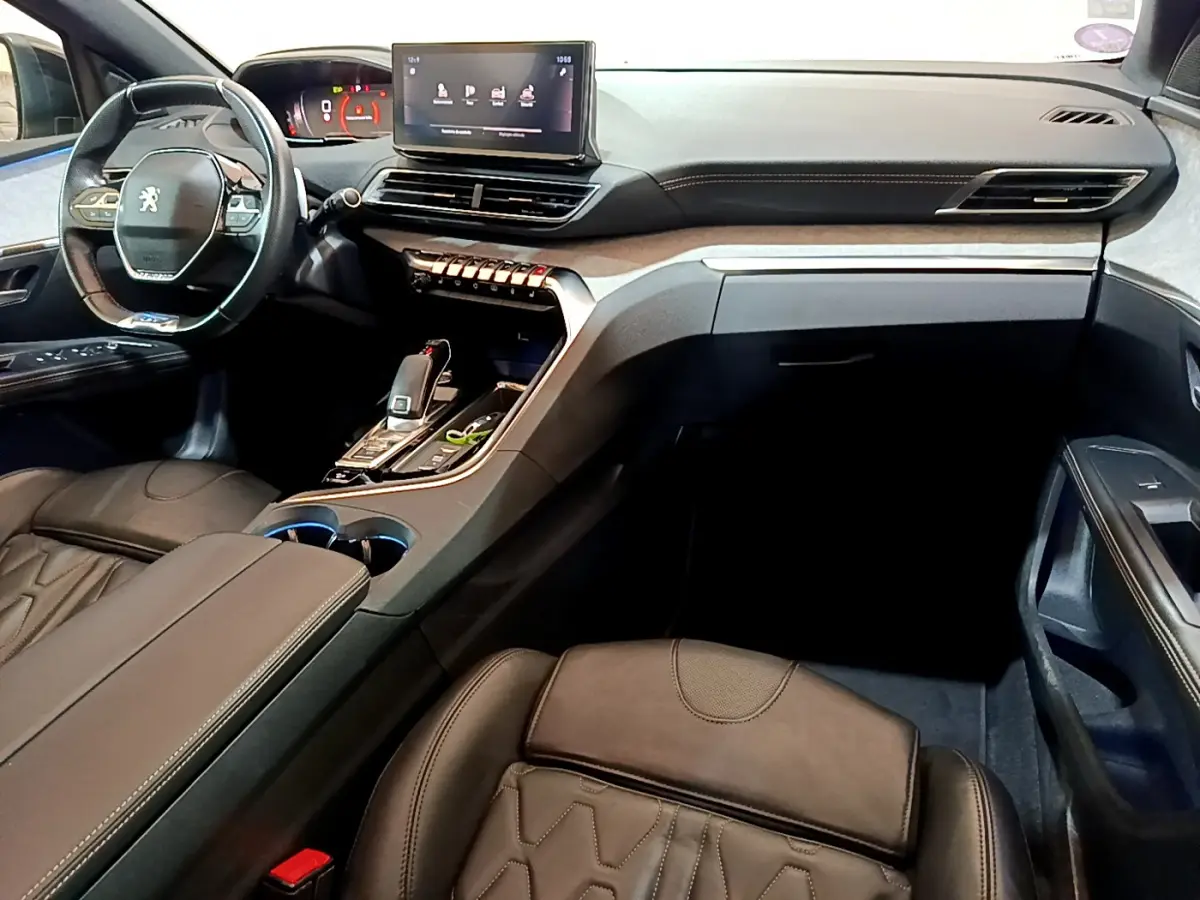 Intérieur du Peugeot 5008 GT 2021 vu côté passager, avec tableau de bord moderne et sièges cuir noirs.