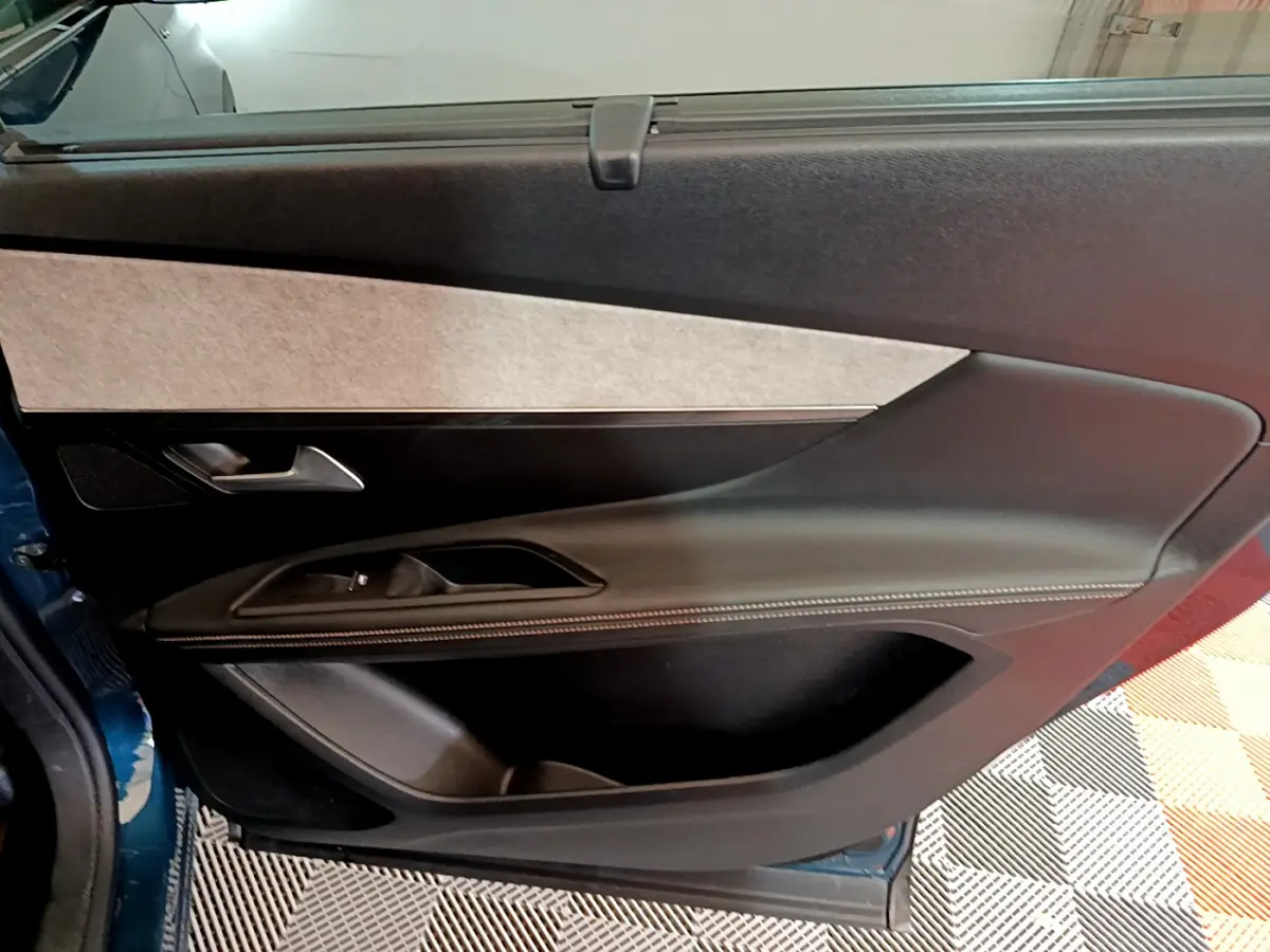 Intérieur côté gauche de la porte arrière bleue du Peugeot 5008 GT 2021, avec garniture noire et surpiqûres blanches.