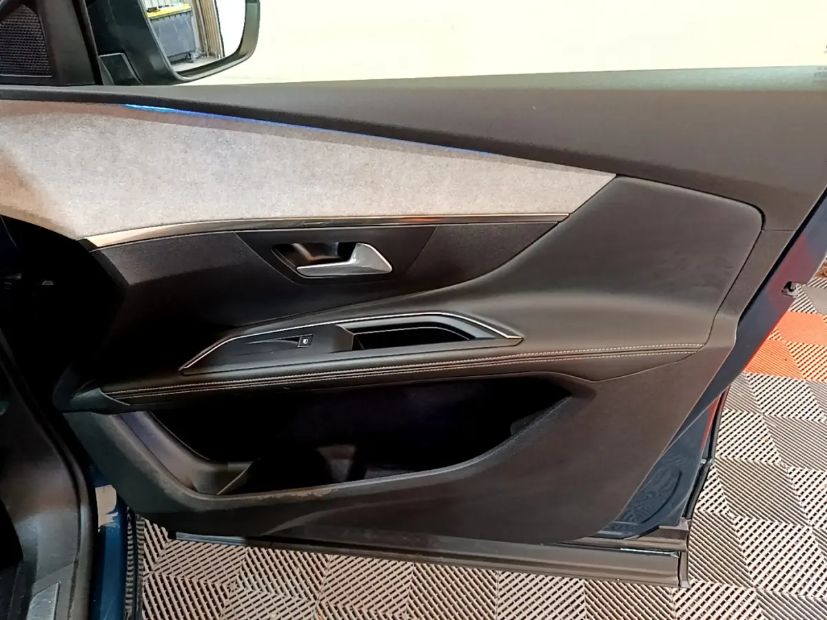 Vue intérieure côté gauche de la porte avant d'un Peugeot 5008 bleu avec garniture noire et grise élégante.