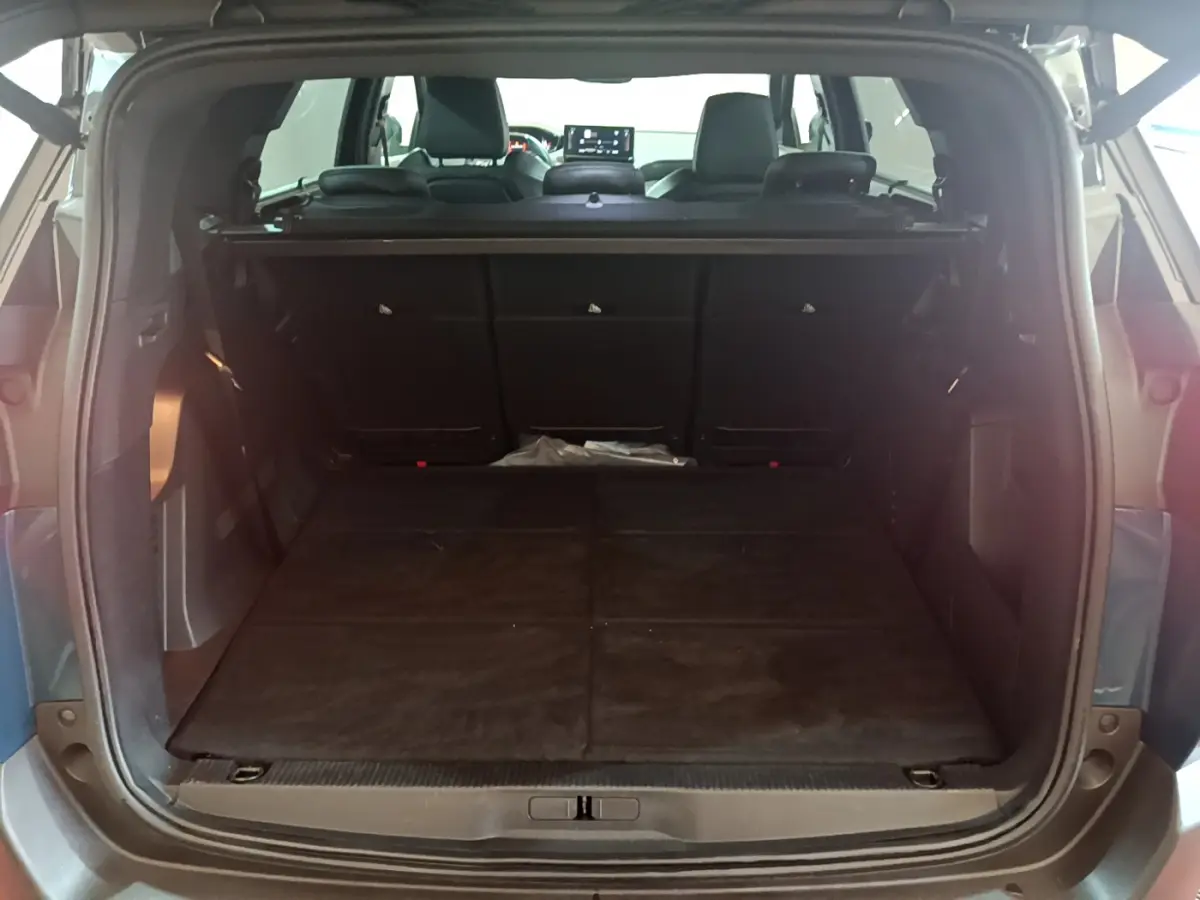 Coffre ouvert du Peugeot 5008 bleu, vue arrière, montrant l'espace de chargement avec sièges rabattus et plancher plat.