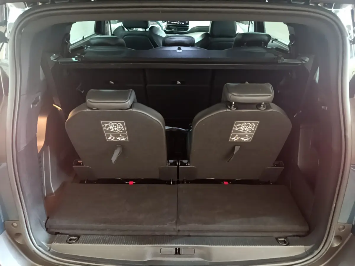 Vue arrière du coffre ouvert d'un Peugeot 5008 bleu 2021, montrant la 3ème rangée de sièges individuels rabattus.
