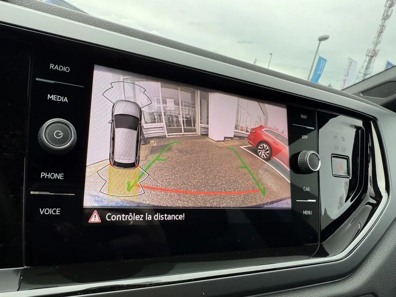 Écran tactile intérieur affichant la caméra de recul du Volkswagen Polo bleu récif métallisé avec aide au stationnement active.