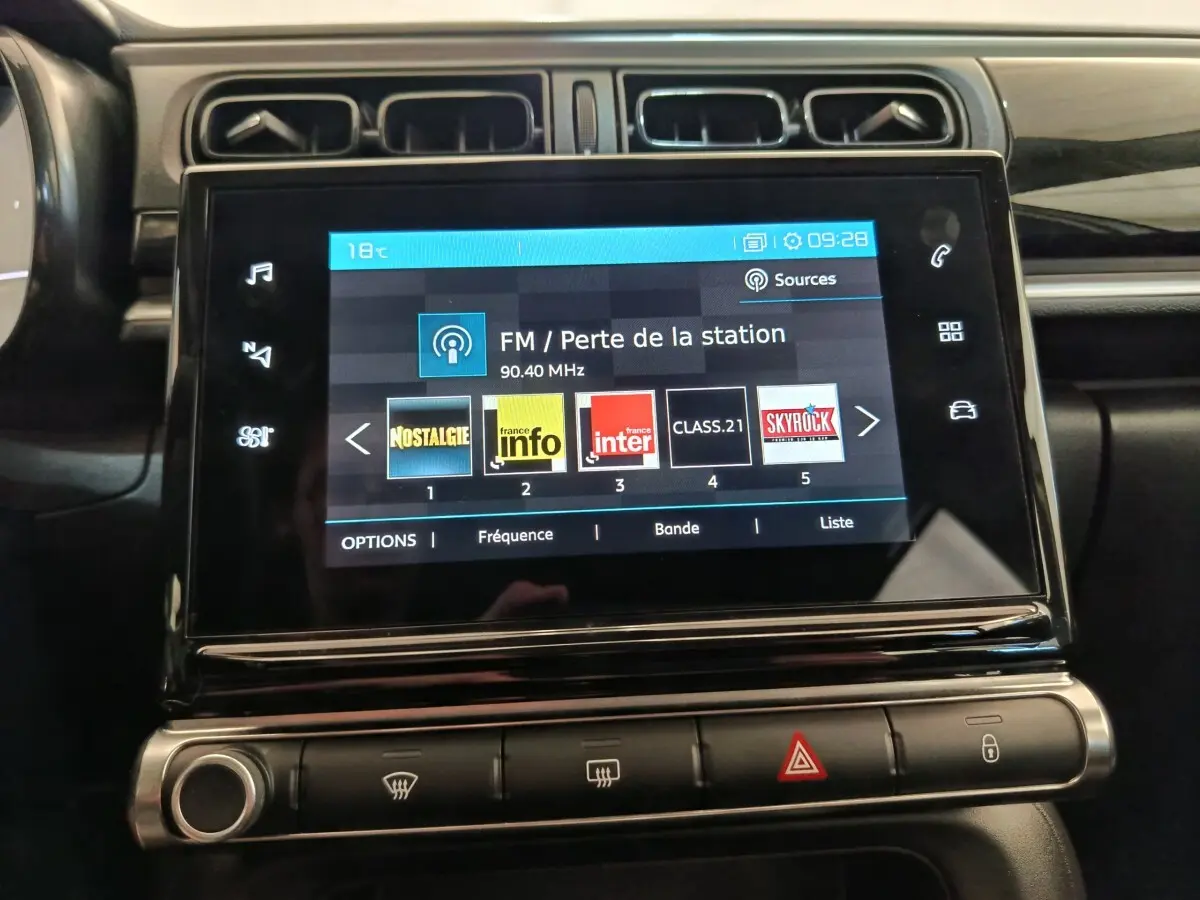 Écran tactile central de 7 pouces du tableau de bord de la Citroën C3 blanche, affichant les stations radio FM.