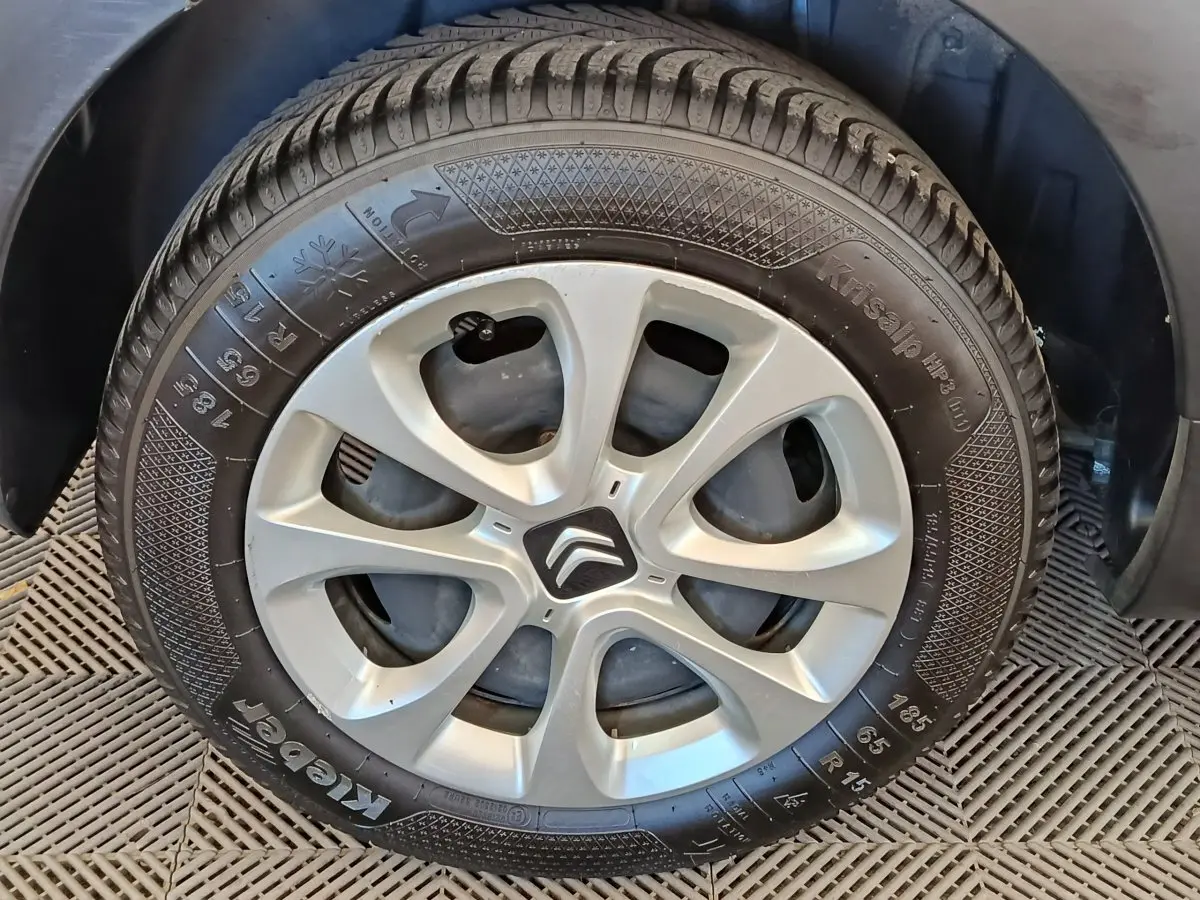 Gros plan sur la roue arrière droite d'une Citroën C3 blanche, montrant le pneu et l'aile du véhicule.