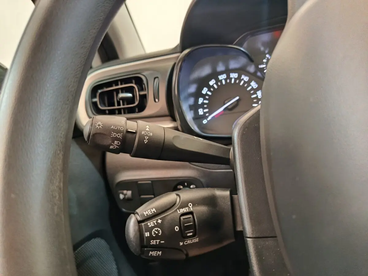 Vue rapprochée du tableau de bord côté gauche de la Citroën C3 blanche, montrant les commandes de régulateur et phares.