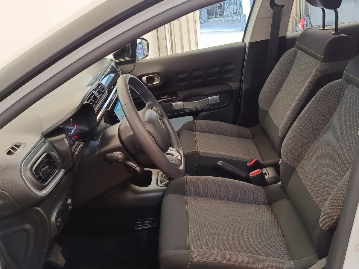 Intérieur avant de la Citroën C3 blanche 2020, vue côté conducteur montrant sièges et tableau de bord moderne.