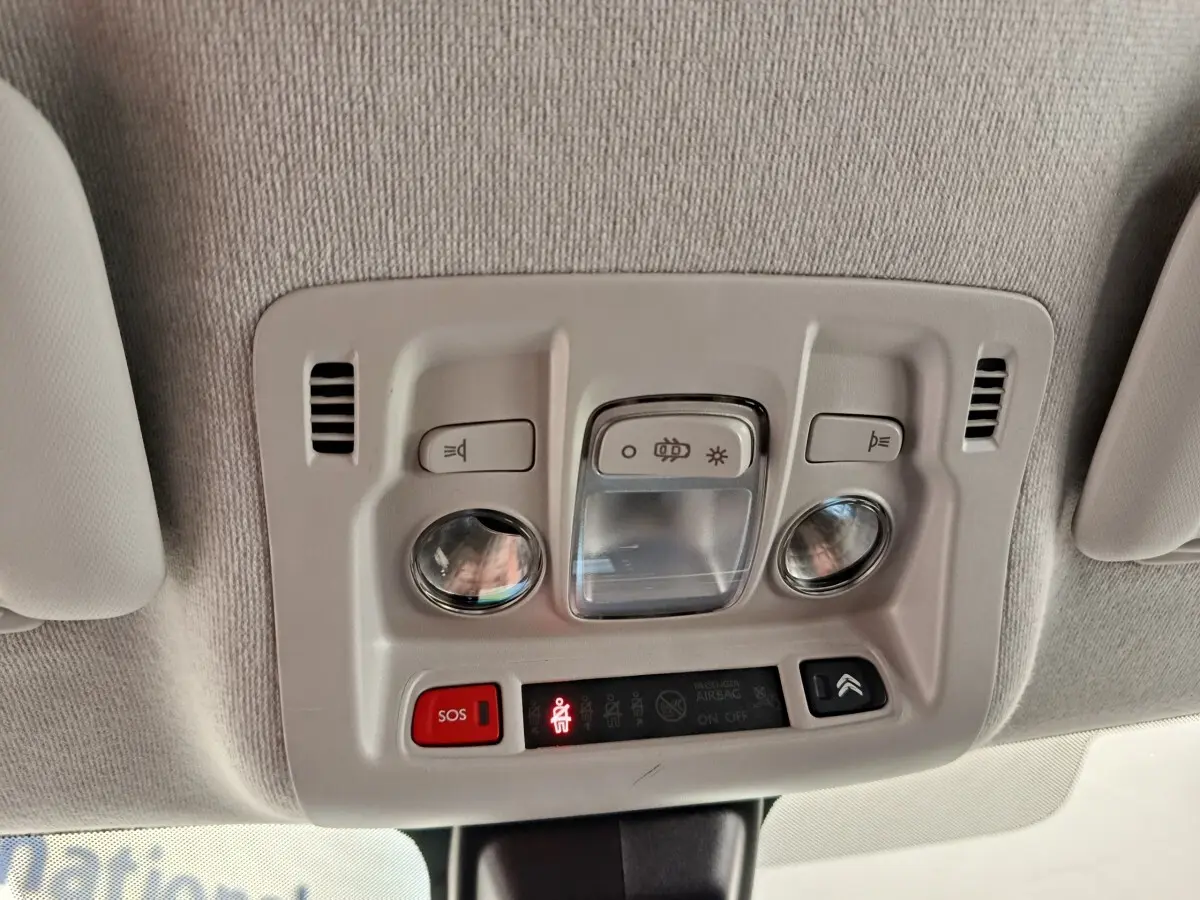 Plafonnier intérieur avec commandes d’éclairage et bouton SOS dans une Citroën C3 blanche, vue du plafond vers l’avant.