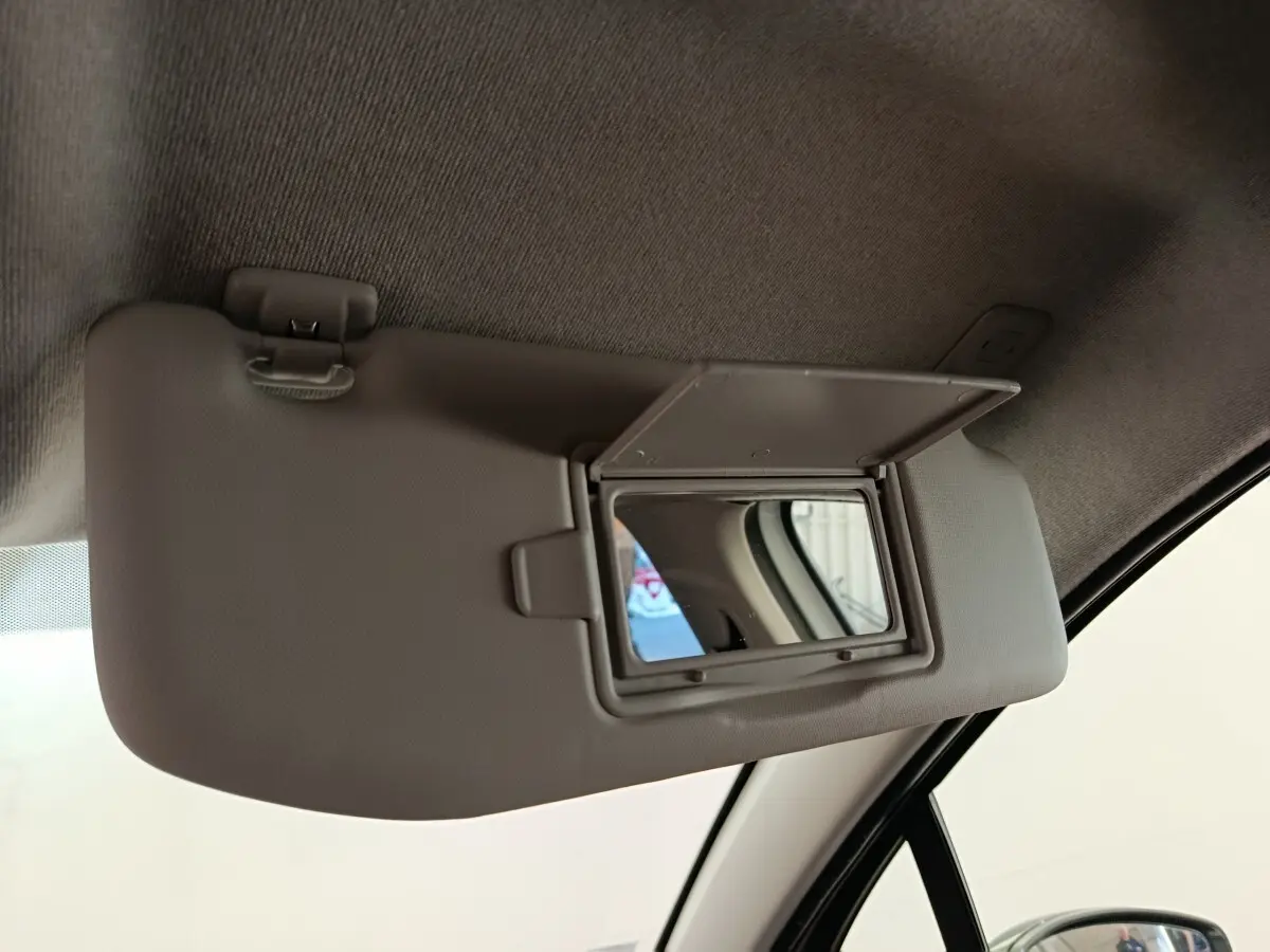 Miroir de courtoisie ouvert sur le pare-soleil côté conducteur d'une Citroën C3 blanche, vue intérieure rapprochée.