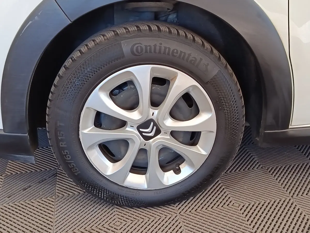 Gros plan sur la roue avant gauche d'une Citroën C3 blanche, avec jante argentée et logo Citroën central.