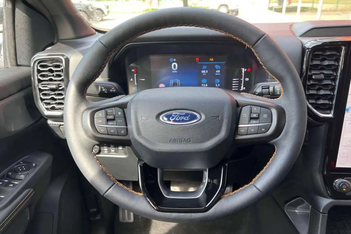 Vue rapprochée du volant cuir noir avec surpiqûres marron et tableau de bord digital du Ford Ranger Wildtrak 2025.