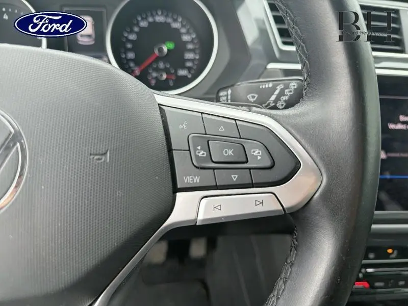 Gros plan sur le volant cuir noir du Volkswagen Tiguan 1.5 TSI 2021 avec commandes multifonctions côté droit.