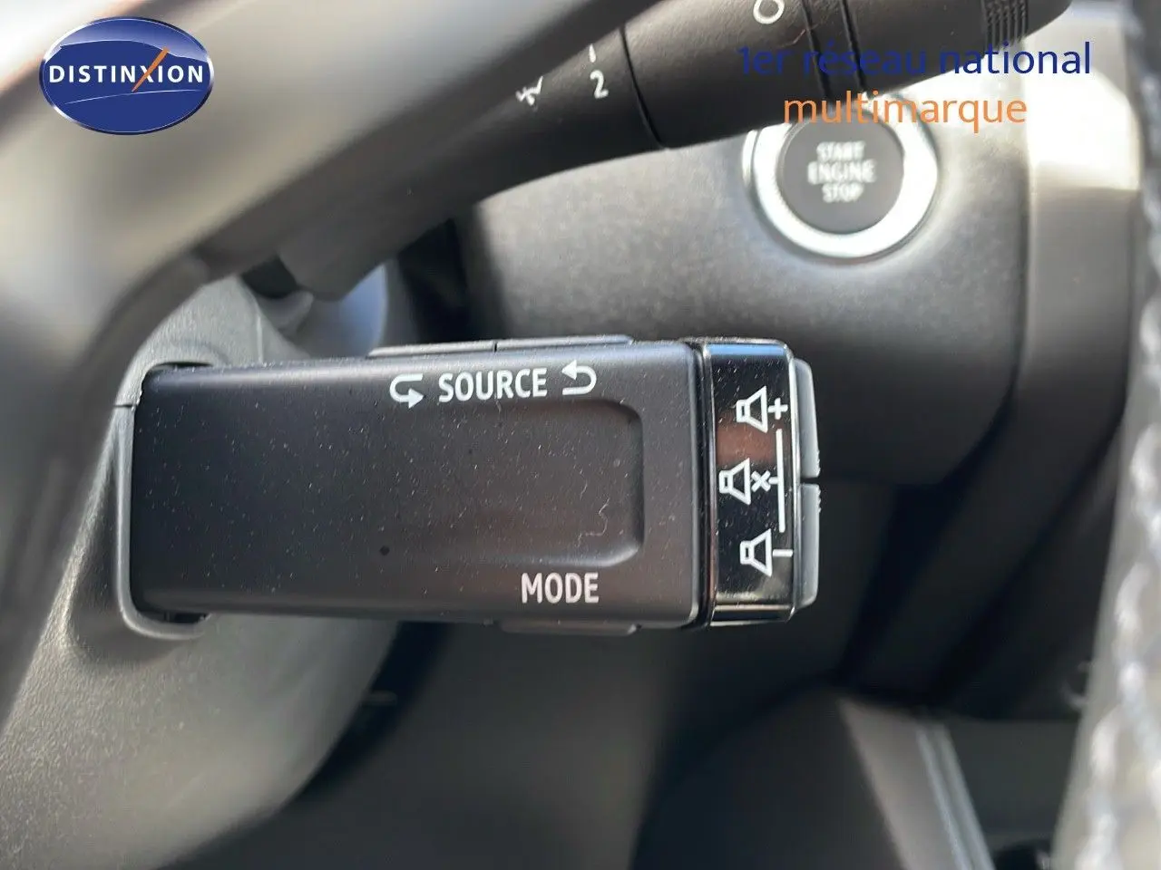 Gros plan sur la commande au volant du Renault Captur 2025, avec boutons source et mode visibles, intérieur noir.