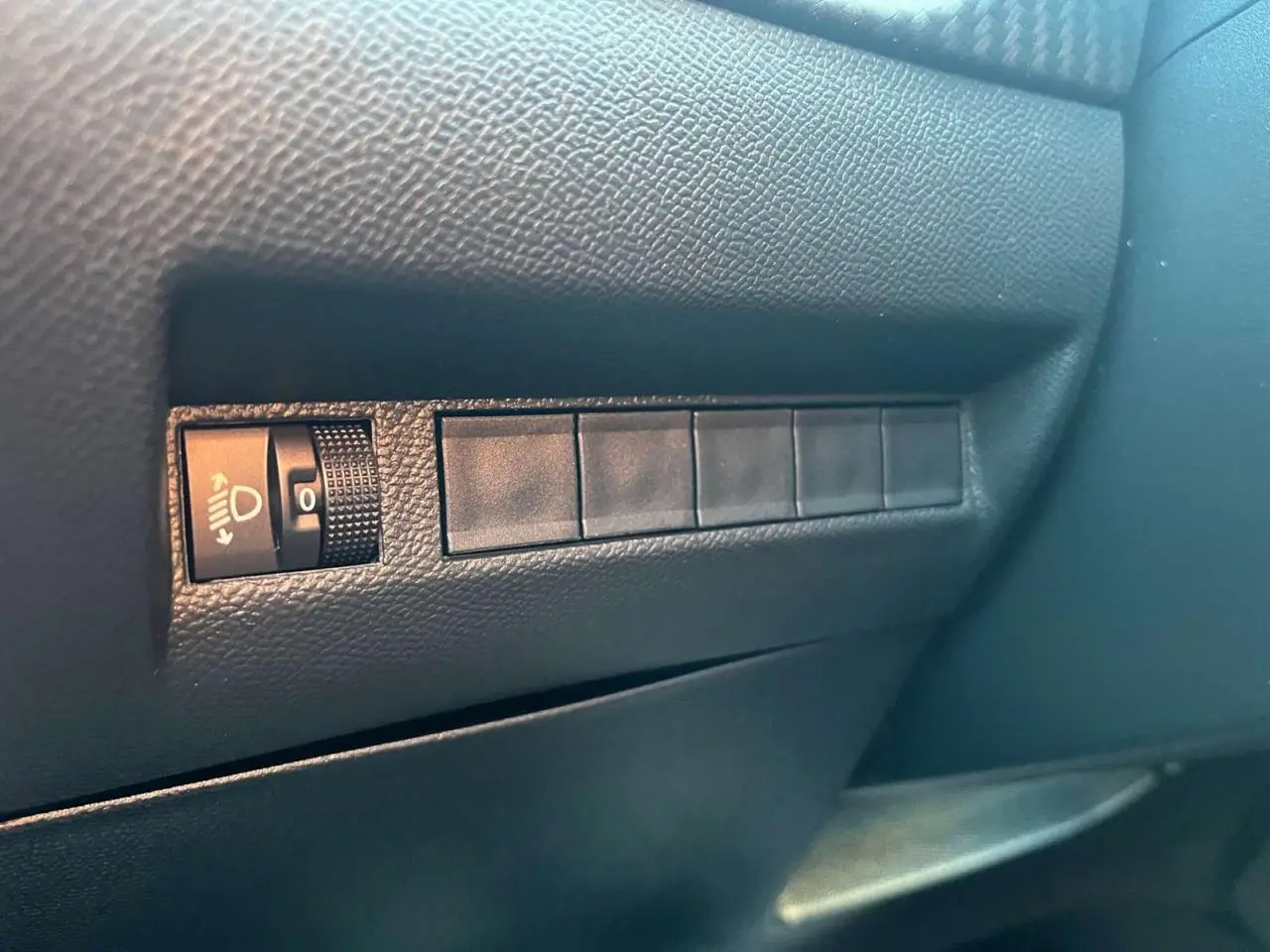 Détail du tableau de bord côté gauche du Peugeot 2008 2024 bleu Vertigo Metal avec réglage des phares.