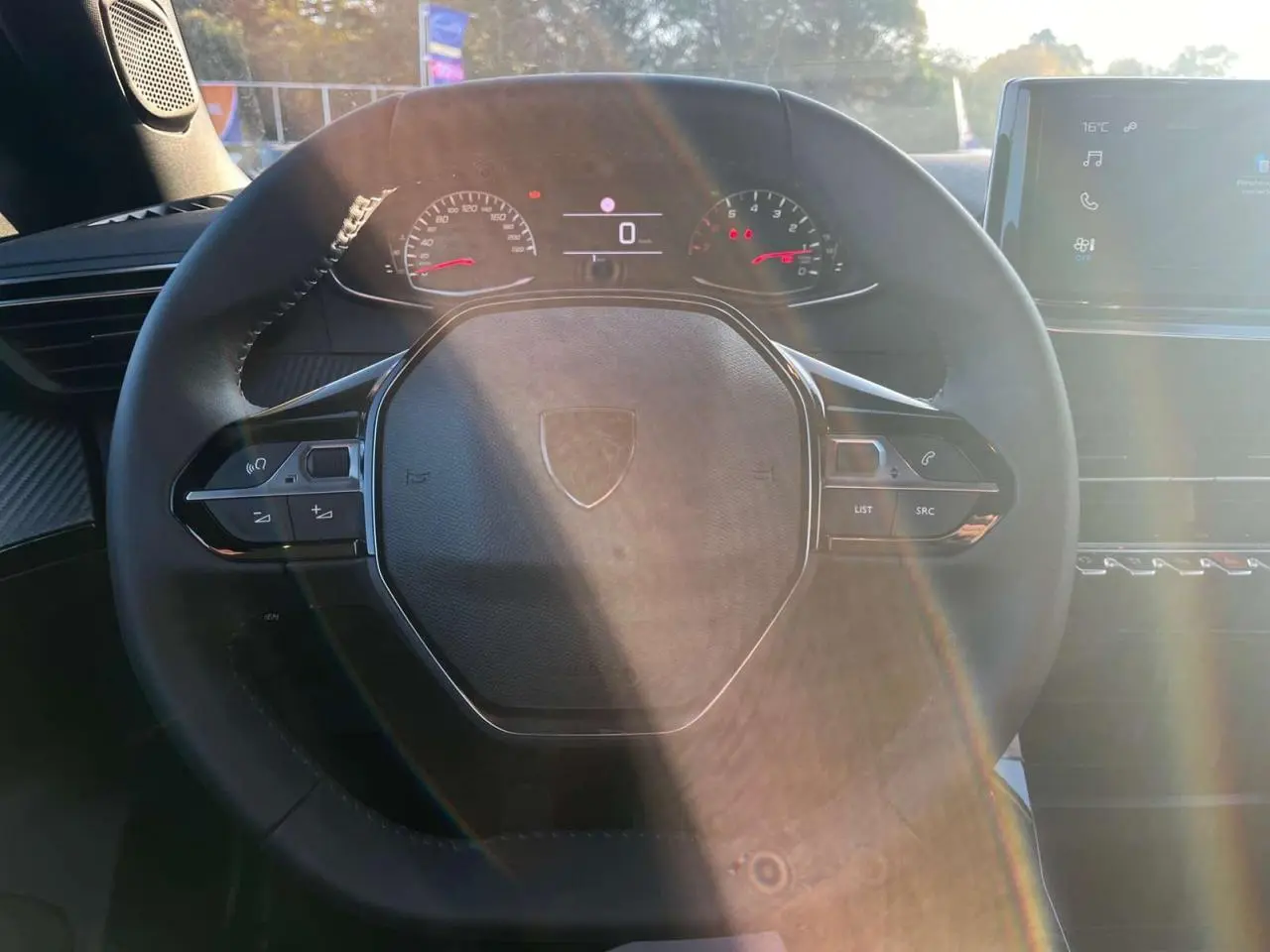 Vue rapprochée du volant multifonction noir du Peugeot 2008 2024 avec tableau de bord numérique et écran tactile.