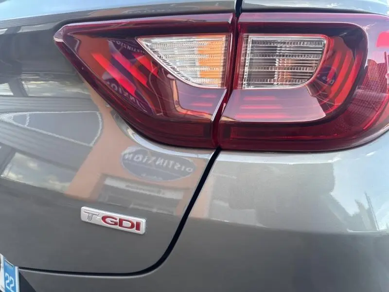 Gros plan sur le feu arrière droit et le logo T-GDI d’une Kia Stonic brun Sienne, vue arrière côté droit.