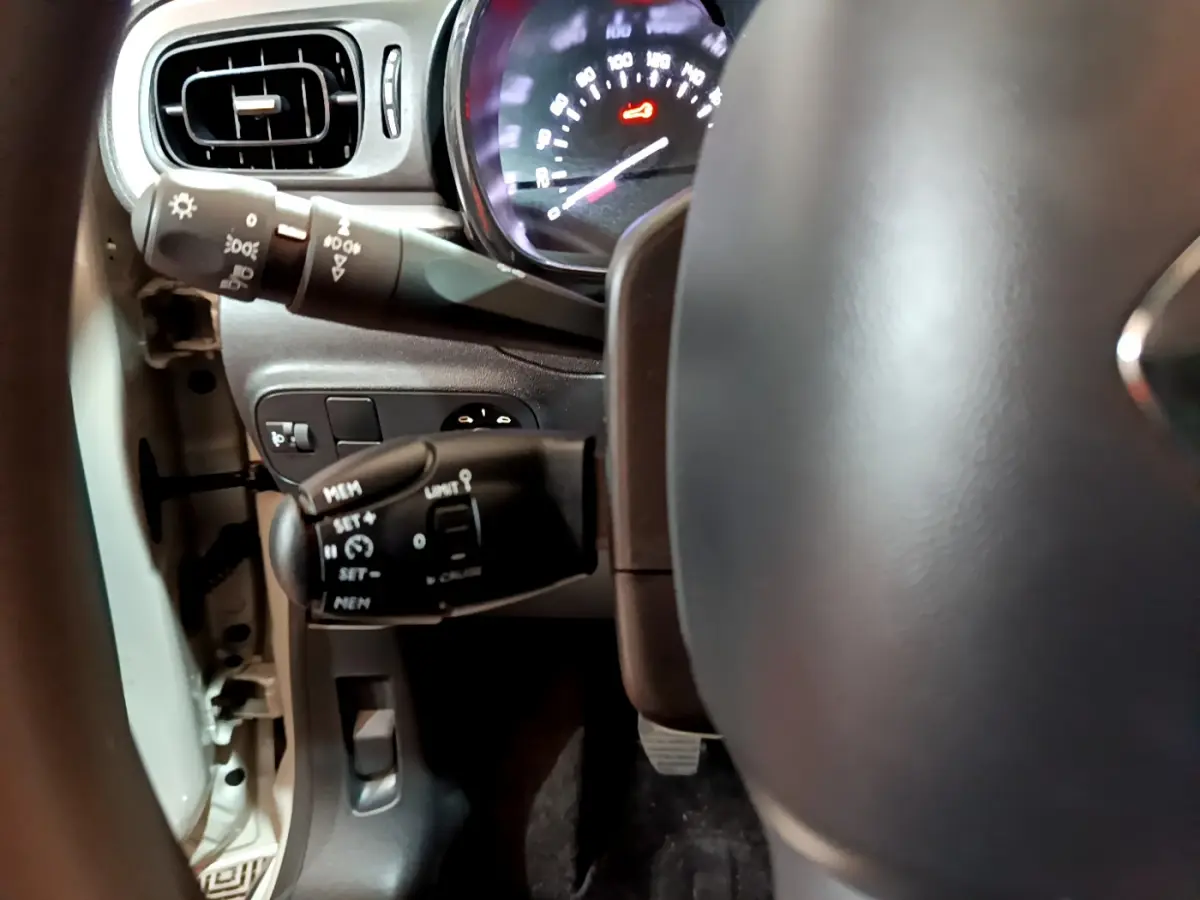 Gros plan sur le tableau de bord et commandes au volant d'une Citroën C3 beige 2022, affichage digital visible.