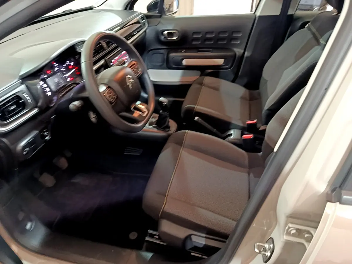 Intérieur de la Citroën C3 beige 2022 vu côté conducteur, avec tableau de bord numérique et sièges gris foncé.