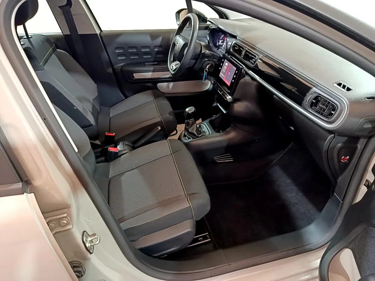 Intérieur de la Citroën C3 beige vue côté conducteur, montrant sièges noirs et tableau de bord avec écran tactile.