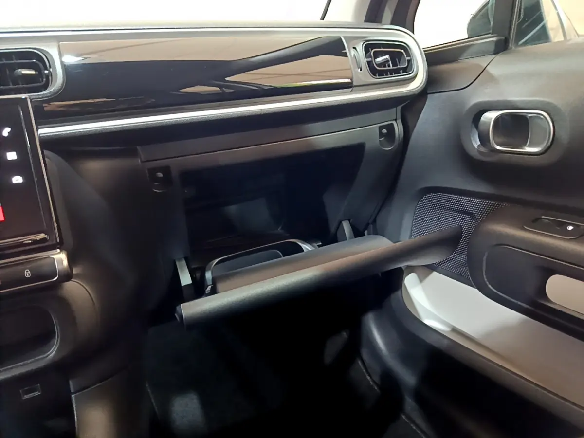 Intérieur de la Citroën C3 beige 2022, vue côté passager sur la boîte à gants ouverte et tableau de bord noir brillant.