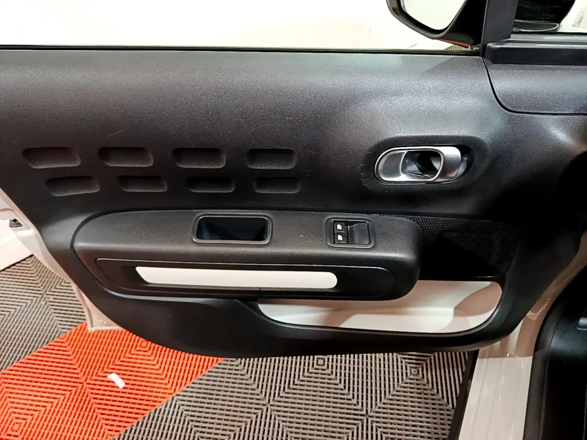 Gros plan sur la porte côté conducteur beige de la Citroën C3 2022 avec poignée intérieure noire et blanche.